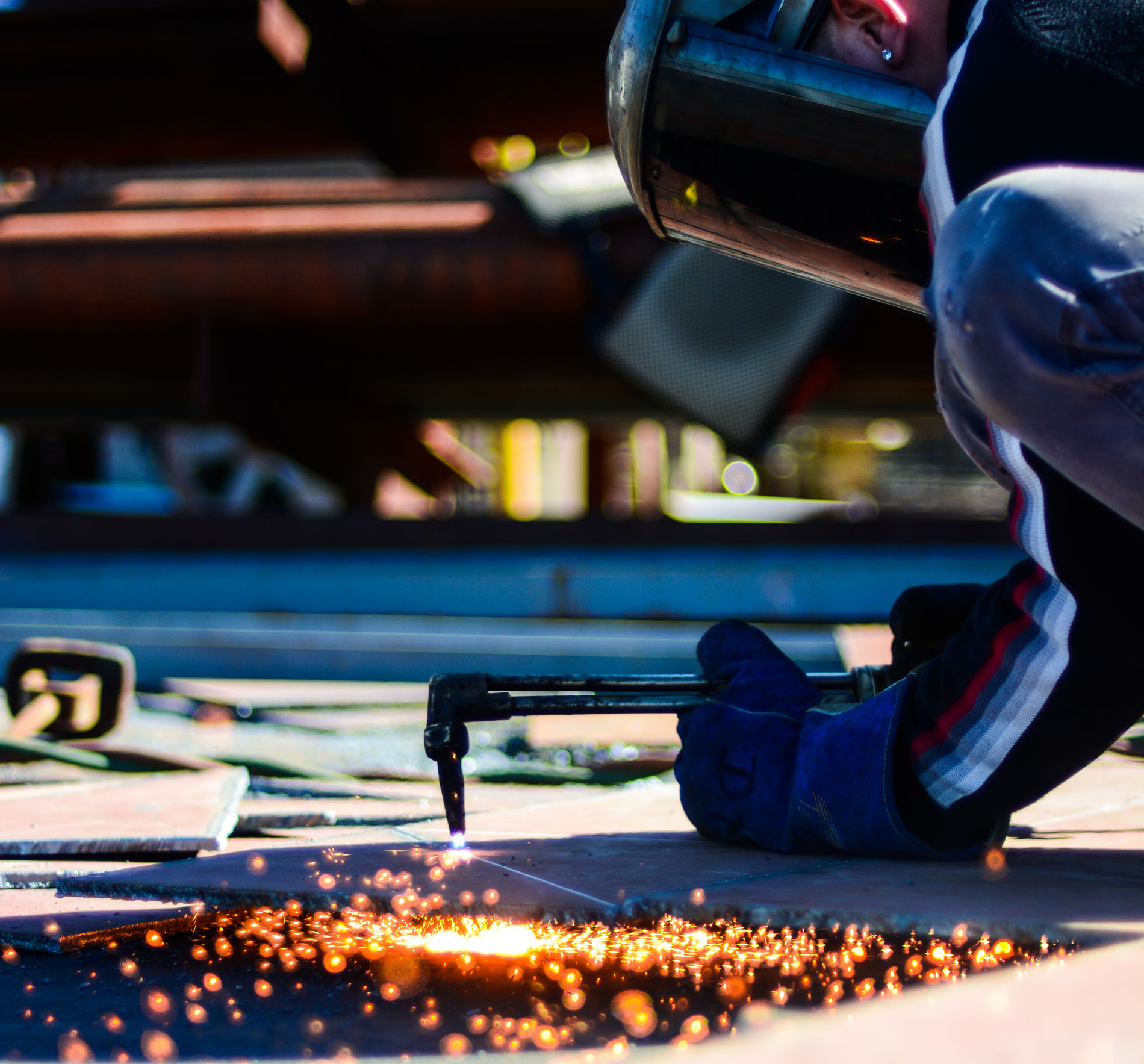 Torch cutting a steel plate with sparks in a fabrication shop