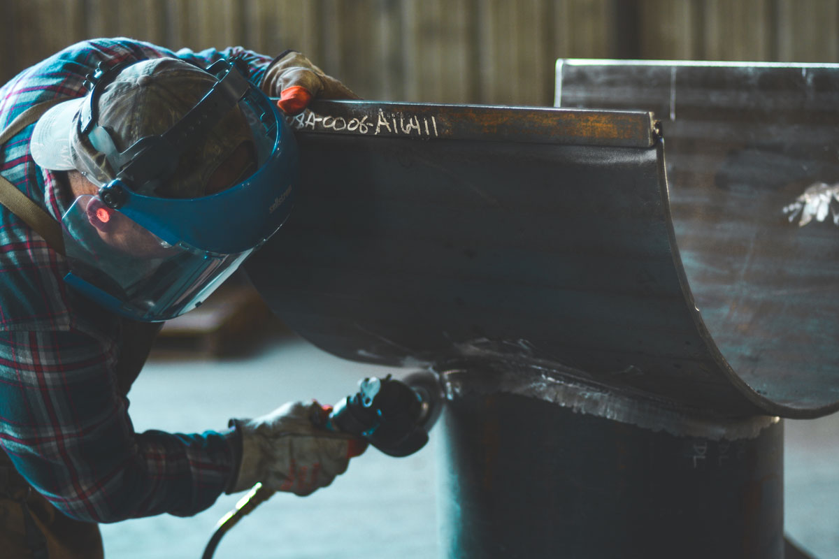Industrial worker grinding a weld seam wearing full protective equipment